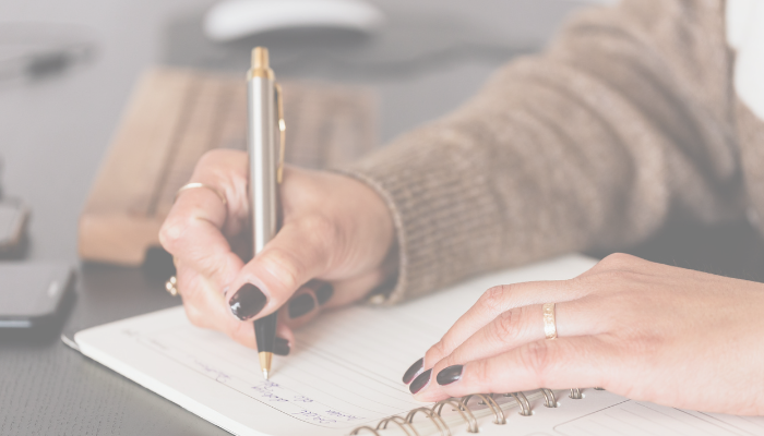 closeup of hand writing in notebook with a pen